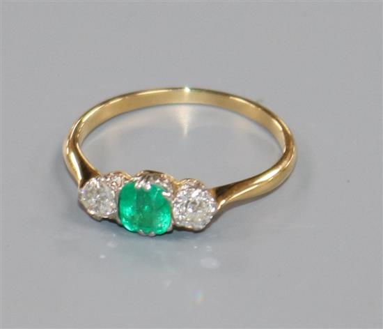 A yellow metal, emerald and diamond three stone ring, size N.